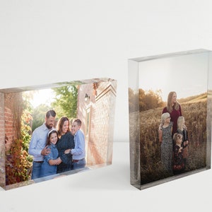 May include: Two glass photo blocks with images of families. The first block shows a family of four standing in a brick courtyard. The second block shows a family of three standing in a field.