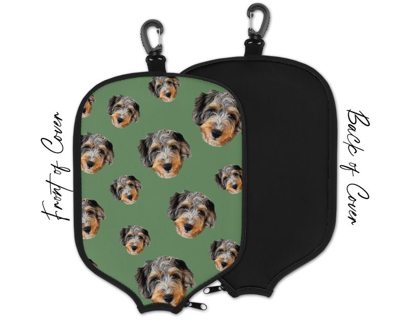 May include: A golf club cover with a repeating pattern of dog faces on a green background. The back of the cover is solid black. Includes a black carabiner clip for easy attachment.