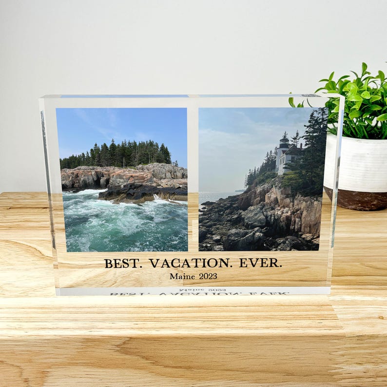 May include: A clear acrylic photo block with two landscape images of the Maine coast. The left image shows a rocky coastline with crashing waves, and the right image features a lighthouse. Text at the bottom reads "BEST. VACATION. EVER. Maine 2023."