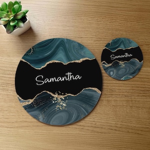May include: A set of two round coasters with a teal and gold marbled design. The larger coaster has the name "Samantha" written in white on a black background. The smaller coaster has the same design and the name "Samantha" written in white on a teal background.