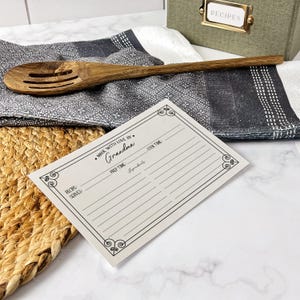 May include: A white recipe card with a black border and the text "Made with love by Grandma". The card has sections for recipe name, servings, prep time, cook time, ingredients, and signature.