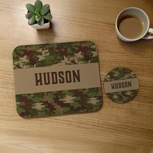 May include: A green and brown camouflage mouse pad with the name "HUDSON" printed in brown on a tan stripe. A matching round coaster with the same design and name is also shown.