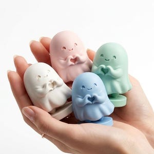 Puede incluir: Colección de cinco figuras de fantasmas en colores pastel. Cada fantasma es de un color diferente: blanco, rosa, azul y verde. Los fantasmas se toman de las manos en forma de corazón. Las figuras son pequeñas y bonitas.