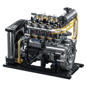 Pode incluir: Um modelo detalhado de um motor, com componentes prateados, pretos e dourados. O motor apresenta peças internas intrincadas, incluindo cilindros, tubos e um volante. É montado numa base preta.