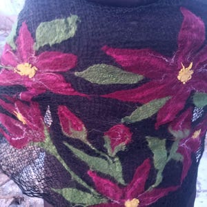 Pu&ograve; includere: Sciarpa nera con grandi fiori magenta in feltro, foglie verdi e centri gialli. Il motivo floreale &egrave; cucito a mano sul tessuto a trama aperta. La sciarpa &egrave; drappeggiata sulle spalle di una persona, mostrando gli intricati dettagli dell'arte tessile.