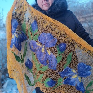 Pu&ograve; includere: Uno scialle fatto a mano, a trama aperta, nei toni dell'oro e del marrone, ornato da grandi fiori di iris blu infeltriti e foglie verdi. Lo scialle ha una delicata trama a pizzo e un vivace design floreale. Un accessorio unico.