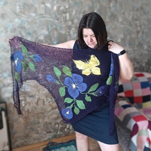 Pu&ograve; includere: Uno scialle viola scuro con disegni floreali e a farfalla. Lo scialle presenta grandi fiori blu con foglie verdi e una farfalla gialla. Lo scialle &egrave; realizzato in un materiale morbido e leggero.