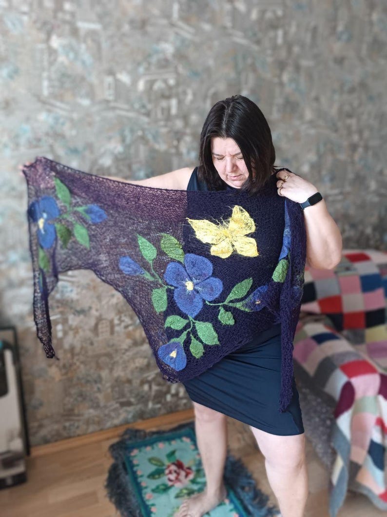 Pu&ograve; includere: Uno scialle viola scuro con disegni floreali e a farfalla. Lo scialle presenta grandi fiori blu con foglie verdi e una farfalla gialla. Lo scialle &egrave; realizzato in un materiale morbido e leggero.