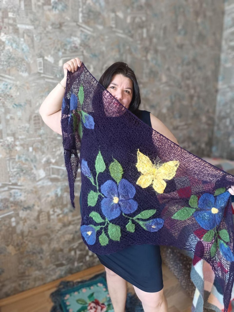 Pu&ograve; includere: Uno scialle blu scuro con disegni floreali e a farfalla. Lo scialle presenta grandi fiori blu con foglie verdi e una farfalla gialla. Lo scialle &egrave; realizzato in un materiale simile a una rete.