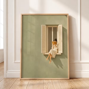 May include: A framed wall art print featuring a sage green wall with an open window. A person in a cream-colored dress sits on the window ledge, reading an open book. The window has light-colored wooden shutters and casts a long, sharp shadow.
