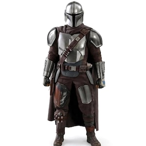 May include: A collectible action figure of a warrior wearing a metallic silver helmet and chest armor over a dark brown fabric suit. The figure features shoulder pauldrons, gauntlets, a utility belt with a diagonal strap, and a long brown cape.