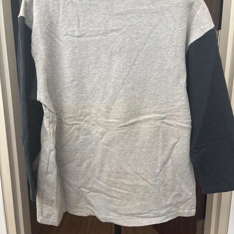 May include: A gray long-sleeved shirt with black sleeves. The shirt is made of a soft material and has a crew neck. The sleeves are a solid black color, while the body of the shirt is a heather gray.