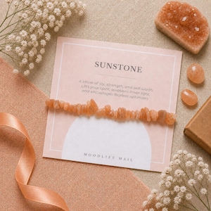 May include: A bracelet made of small, irregular, orange-toned sunstone chips attached to a rectangular display card. The card features the text SUNSTONE, a descriptive paragraph, and the brand name MOODLIFT MAIL at the bottom in black font.