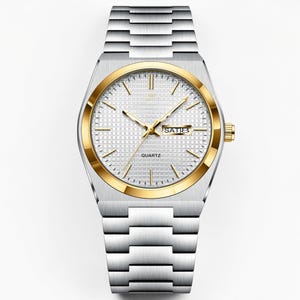 May include: A silver-toned quartz watch with a gold-colored bezel and hands. The watch face is white with a grid pattern and displays the day of the week. The watch has a silver-toned metal band.
