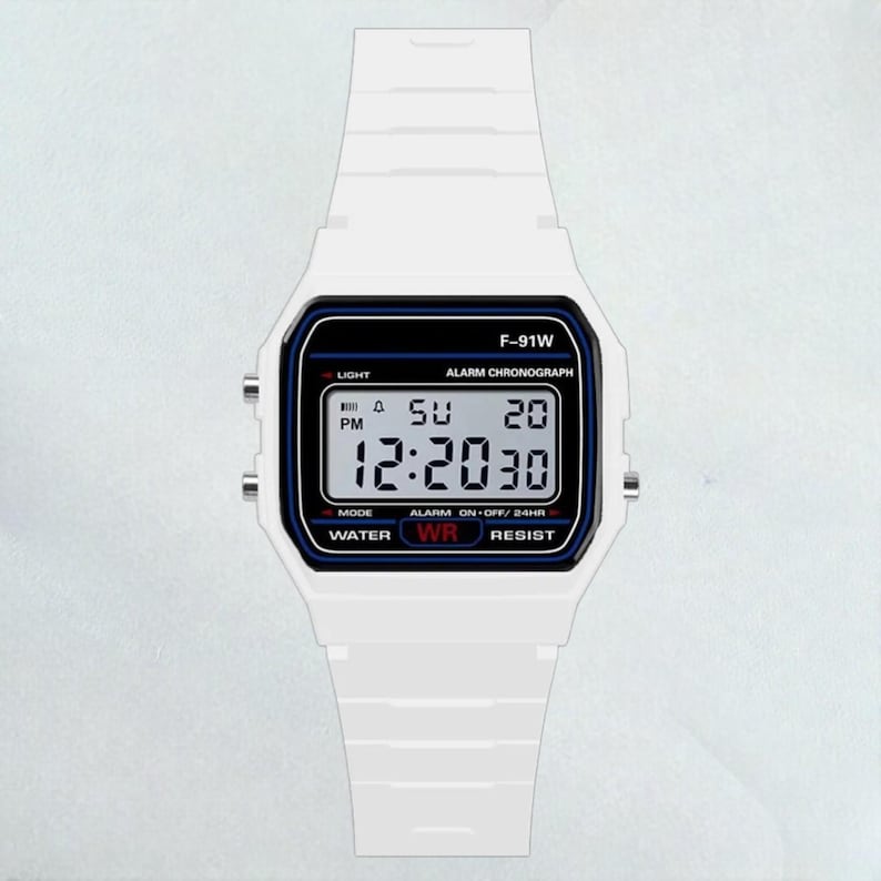 May include: White digital watch with a rectangular face and a white strap. The watch face displays the time, day, and date. The watch has the text "F-91W" and "ALARM CHRONOGRAPH". The watch is water resistant.