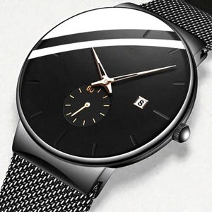 以下が含まれることがあります： メッシュバンドの黒い腕時計。文字盤は黒で、金色の針と小さな秒針が付いています。時計には日付表示があり、上部に白いストライプがあります。ケースは黒い金属製です。