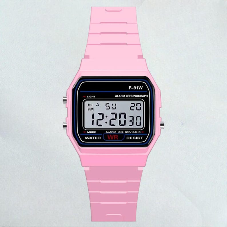 May include: A pink digital watch with a black rectangular face. The watch displays the time as 12:20:30, with the day and date visible. The watch band and case are a solid pink color, and the watch has the text "F-91W" on the top.