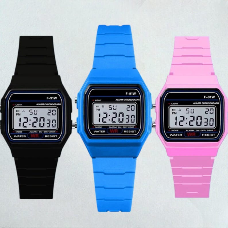 May include: Three digital watches in black, blue, and pink. Each watch displays the time 12:20:30 and features a rectangular face with a matching colored band. The watches have the text "F-91W" and "WATER WR RESIST".