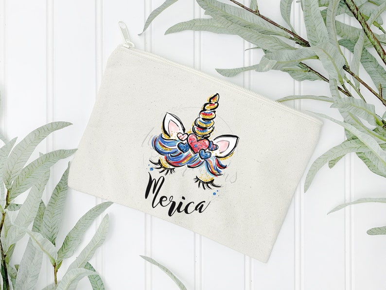 May include: A white canvas zippered pouch with a colourful unicorn illustration and the word "Merica" printed on it.