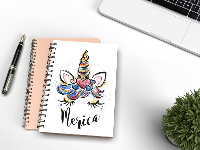 May include: A white spiral notebook with a colourful unicorn illustration and the word "Merica" on the cover. The unicorn has a blue, red and white mane and tail with glitter accents. The unicorn has pink ears and a gold horn.