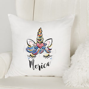 May include: White cushion featuring a colourful unicorn illustration and the word "Merica" printed on it.