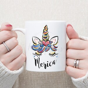 May include: White ceramic mug featuring a colourful unicorn design and the word "Merica" printed on the front.