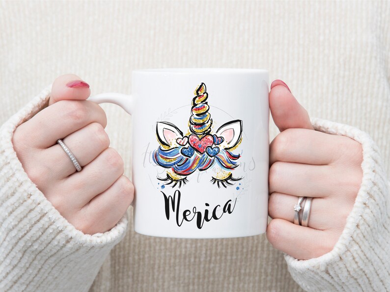 May include: White ceramic mug featuring a colourful unicorn design and the word "Merica" printed on the front.