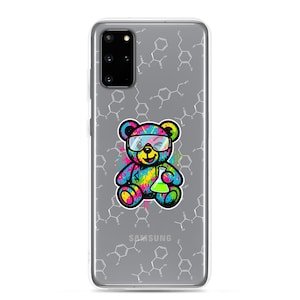 May include: A clear phone case featuring a colorful cartoon teddy bear wearing safety glasses and holding a green beaker. The bear is decorated with rainbow paint splatters. The background has a pattern of white chemical structures, and the Samsung logo is visible.