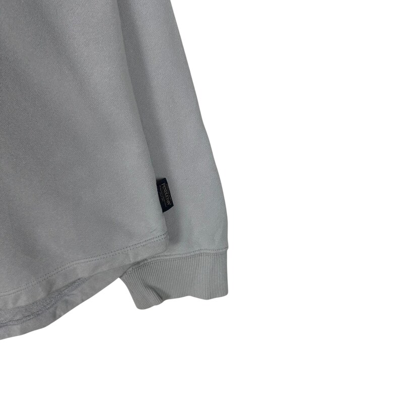 Puede incluir: Una sudadera gris claro con pu&ntilde;o acanalado y una peque&ntilde;a etiqueta negra en la manga. La etiqueta tiene texto blanco. La sudadera est&aacute; hecha de un material suave.