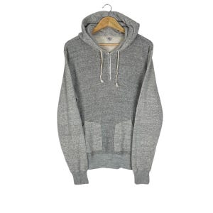 May include: A grey hooded sweatshirt with a front pocket and a half-zip. The sweatshirt features a drawstring hood and ribbed cuffs and hem. The garment is displayed on a hanger against a white background.