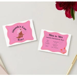 Op de afbeelding: Twee roze en witte uitnodigingen met een rodeo-thema. Op één staat "Amanda's Last Rodeo" met een afbeelding van een cowboylaars en hoed. De andere zegt "Miss to Mrs" met evenementdetails en een hoefijzer. Een gouden pen en een bloem staan ook in de afbeelding.