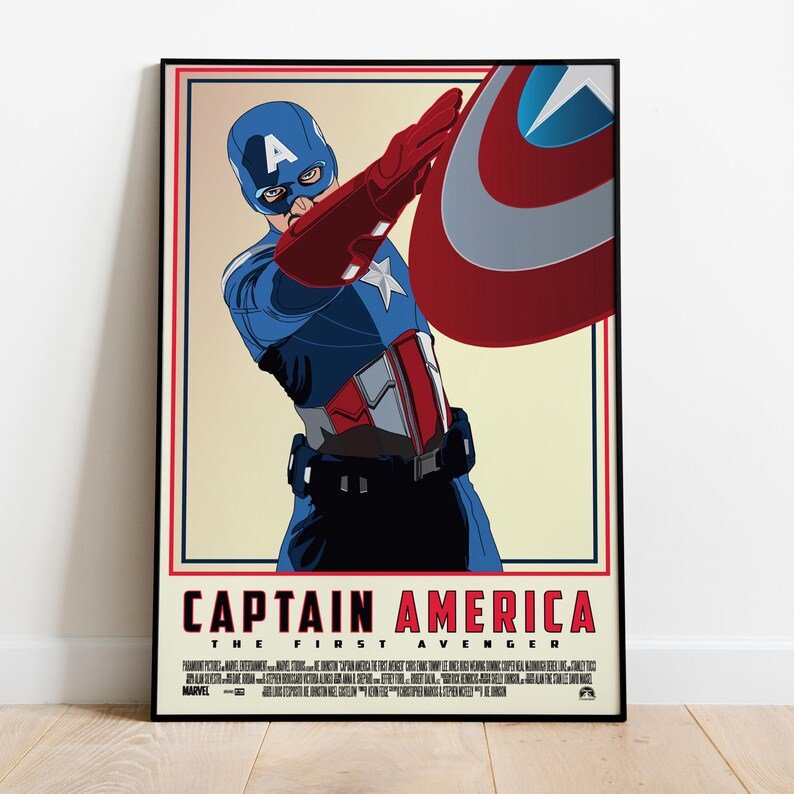 May include: A framed poster featuring Captain America from "The First Avenger." The artwork depicts Captain America in his blue, red, and white costume, holding his shield. The poster has a cream-colored background and a red and black border.