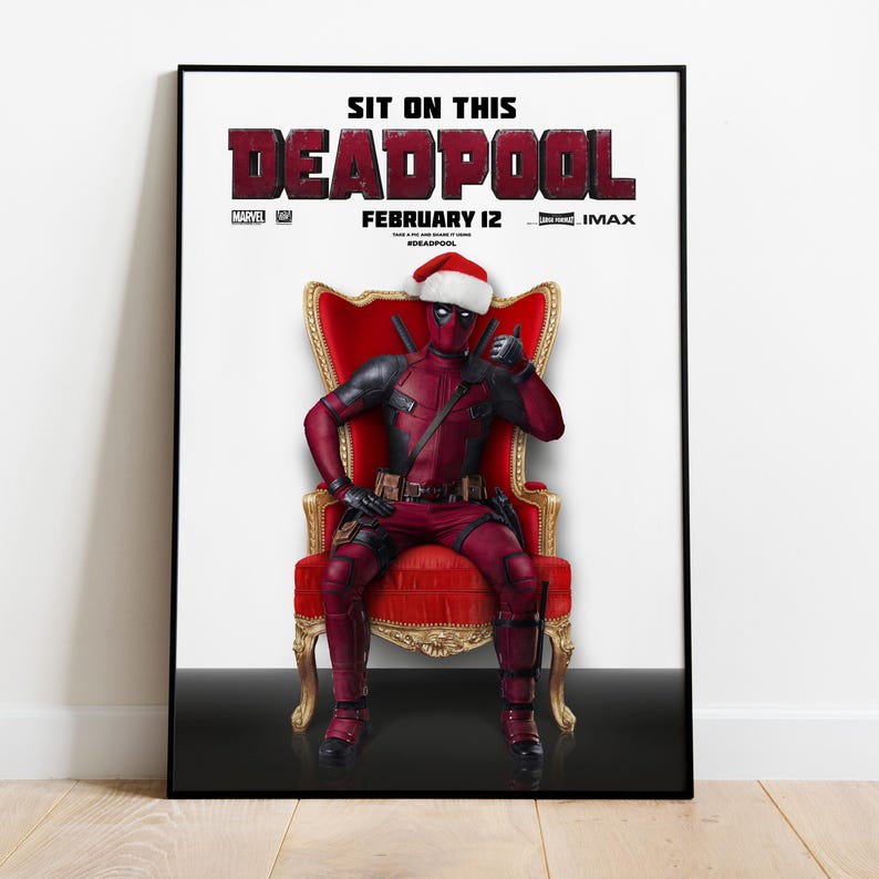 May include: A framed poster featuring Deadpool in a Santa hat, seated on a red throne. The poster's title reads "DEADPOOL" in a bold, textured font, with the text "FEBRUARY 12" below. The Marvel logo is visible.