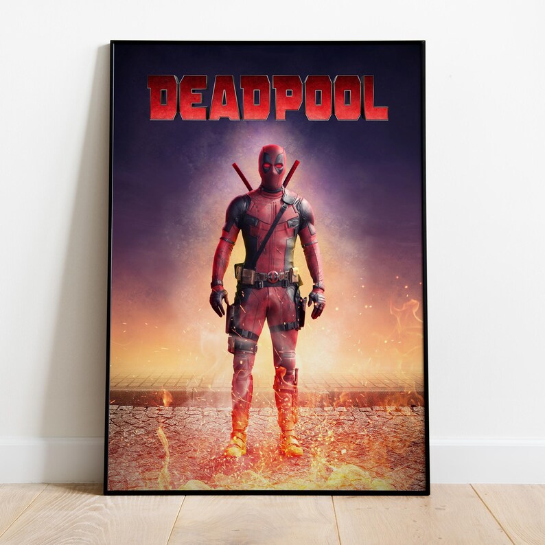 May include: A framed poster featuring the character Deadpool. The character is in a red and black suit, standing in front of a fiery background. The word "DEADPOOL" is displayed in red block letters at the top of the poster.
