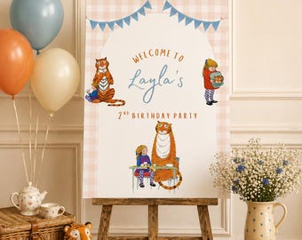 May include: A wooden easel displays a sign that reads "Welcome to Layla's 2nd Birthday Party" with illustrations of a tiger and a girl. Balloons, a stuffed tiger, and books are also visible.