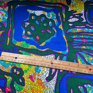 Puede incluir: Una tela colorida con un patr&oacute;n geom&eacute;trico en tonos de verde, azul, amarillo, rosa y blanco. El patr&oacute;n presenta una serie de cuadrados y c&iacute;rculos con una apariencia texturizada, casi como un mosaico.