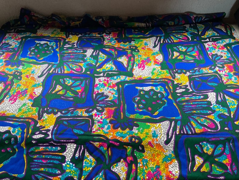 Puede incluir: Una tela colorida con un patr&oacute;n geom&eacute;trico en tonos de azul, verde, amarillo y blanco. El patr&oacute;n presenta formas y l&iacute;neas abstractas.