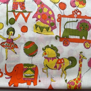 May include: White fabric with a colorful circus-themed print. The design features illustrations of a lion in a cage, an elephant, a giraffe, a horse, a clown, and a ballerina, all in bright orange, pink, yellow, and green.