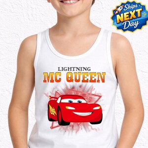 A young boy wearing a white tank top with a graphic of Lightning McQueen from the Cars movie.
