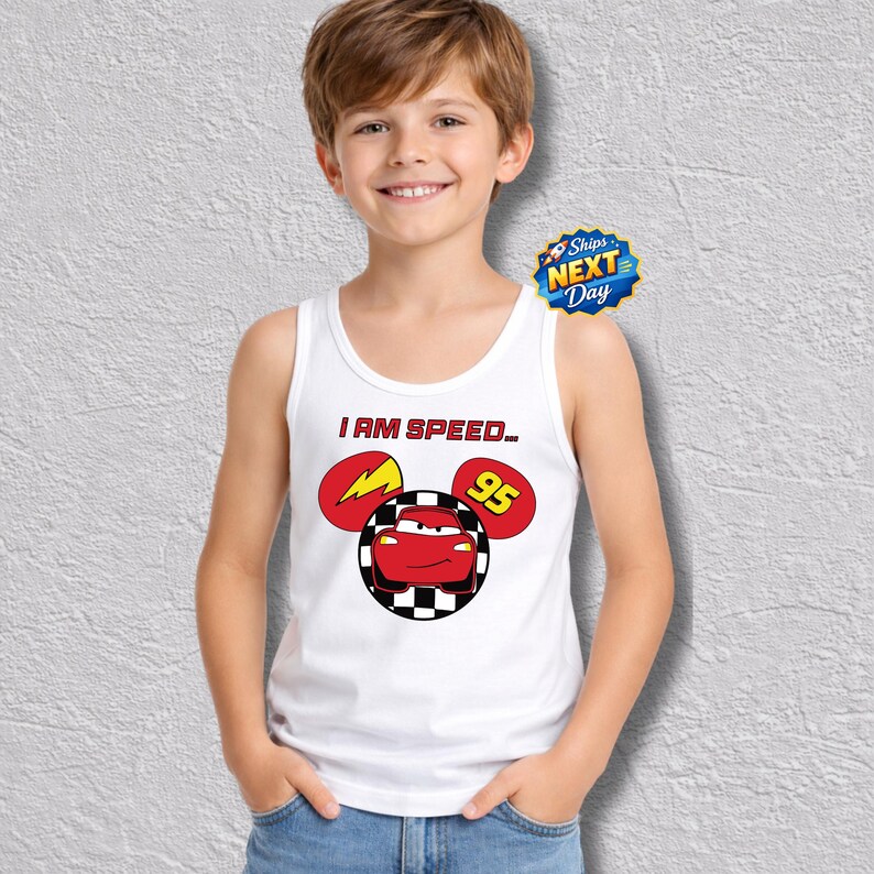 A young boy wearing a white tank top with a graphic of a cartoon character and the text "I AM SPEED 95" is smiling at the camera.