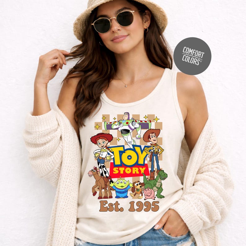 A woman wearing a white tank top with a graphic of characters from the Toy Story movie, posing against a white background.