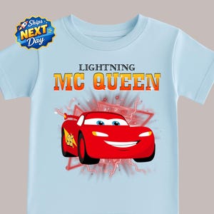 A light blue t-shirt with a graphic of a red car and the text "Lightning MC Queen" printed on it.