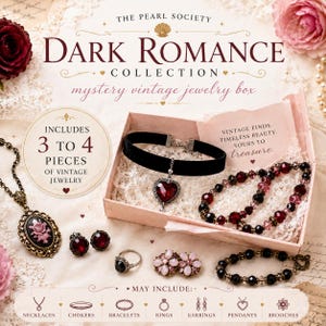Op de afbeelding: Een mystery vintage sieradendoos uit de Dark Romance Collection van The Pearl Society. De doos bevat een zwarte fluwelen choker met een rood hartvormig hangertje, kralenarmbanden in rood en zwart, een camee-ketting, oorbellen en een ring.