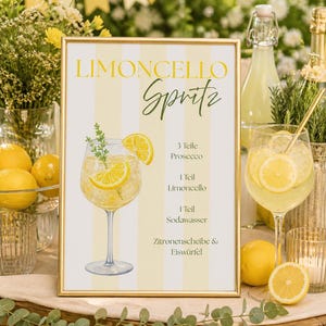 Könnte beinhalten: Ein gerahmtes Schild mit gelb-weißen vertikalen Streifen, das den Text Limoncello Spritz und ein Rezept mit 3 Teile Prosecco, 1 Teil Limoncello, 1 Teil Sodawasser sowie Zitronenscheibe & Eiswürfel neben einer Cocktail-Illustration zeigt.
