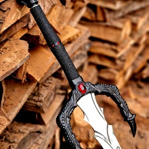 May include: A decorative sword with a black handle and guard, featuring a skull-shaped pommel. The blade is silver with etched designs. A red gem is set in the guard. The sword is leaning against a stack of wood.
