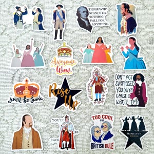 May include: A collection of colorful stickers featuring characters and quotes from the musical Hamilton. The stickers include images of historical figures, crowns, and phrases like "Rise Up" and "Awesome Wow."