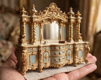 Puede incluir: Un aparador en miniatura ornamentado con espejo, que presenta paneles de color azul claro y tallas decorativas doradas. La pieza incluye dos cajones pequeños, dos armarios laterales y un espejo central. Una taza diminuta y un libro descansan sobre él.