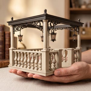Könnte beinhalten: Ein architektonisches Miniaturmodell eines Pavillons mit einem dunkelbraunen Dach, hellbeigen Säulen und einem passenden Balustradengeländer. Vier kleine, hängende Laternen mit dunklen Metallrahmen sind an der verzierten Dachkonstruktion befestigt.