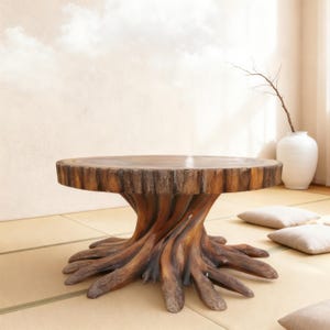 Puede incluir: Una mesa de centro única, hecha a mano, con diseño de tocón de árbol. La mesa presenta una tapa redonda de madera sostenida por una base que imita las raíces y el tronco de un árbol. La mesa tiene aproximadamente 76 cm de diámetro.