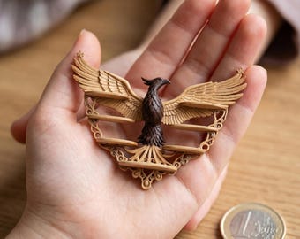 Puede incluir: Una detallada escultura de madera de un ave fénix con las alas extendidas. El ave es marrón con alas color canela y se sostiene en una mano. La escultura tiene detalles intrincados y parece ser un objeto decorativo.